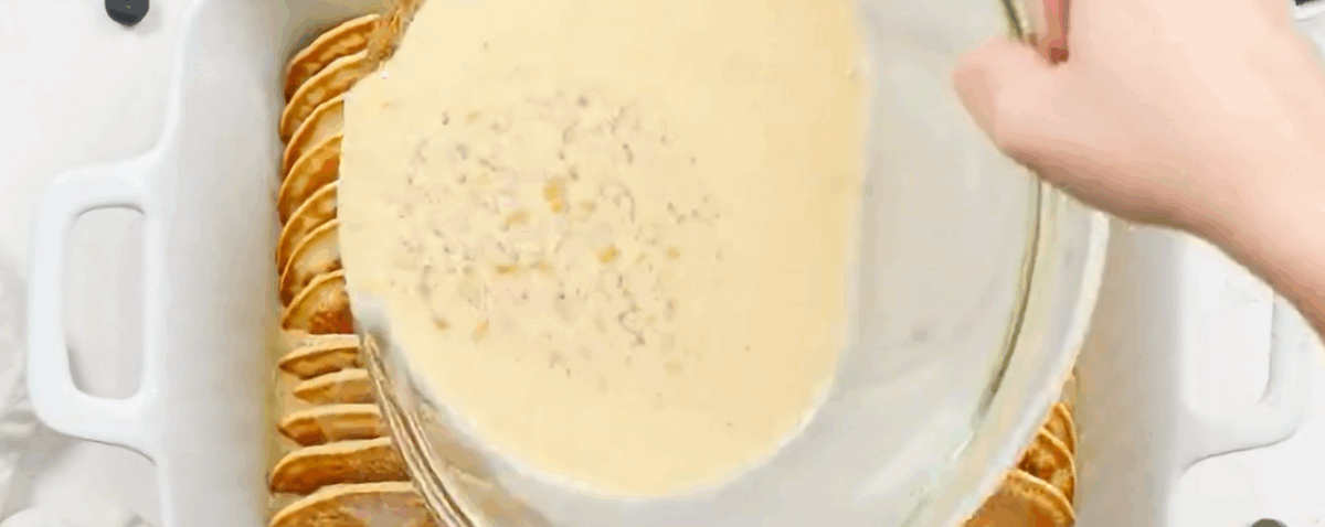 Pouring the custard over the pancakes.