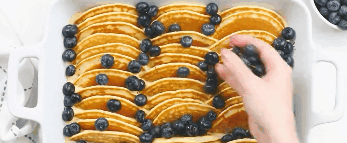 Scattering blueberries over the casserole. 