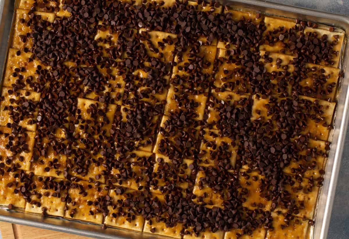 saltine crackers on baking sheet covered with toffee and mini chocolate chips