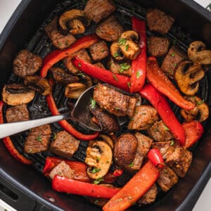 A spoon in air fryer steak and veggies