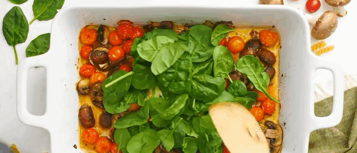 Adding spinach to the pan with the veggies and cheese. 