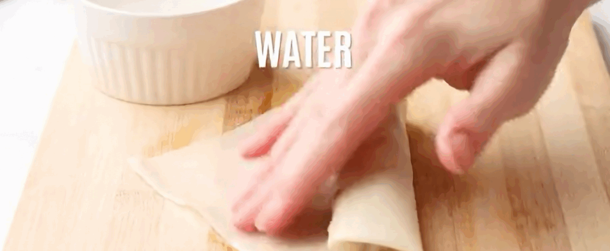 Sealing the rolled lumpia wrapper with water. 
