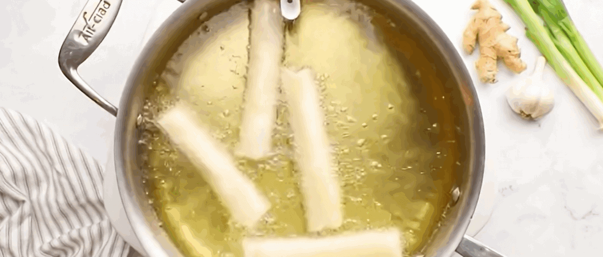 4 lumpia deep frying in a pot. 