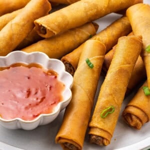 A plate of pork lumpia with a dish of sweet chili sauce