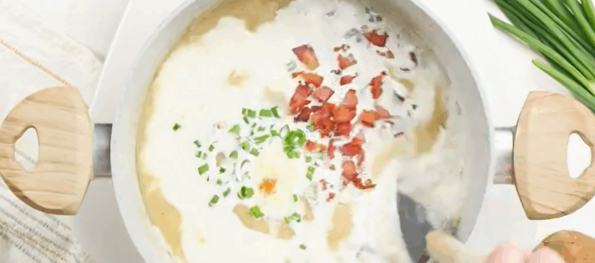 Adding fixings to the soup; bacon, green onions, cheese and cream.