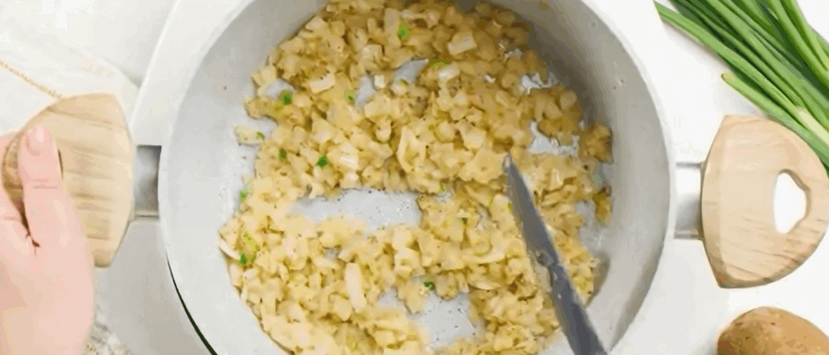 Adding seasonings to the pot with the onions.