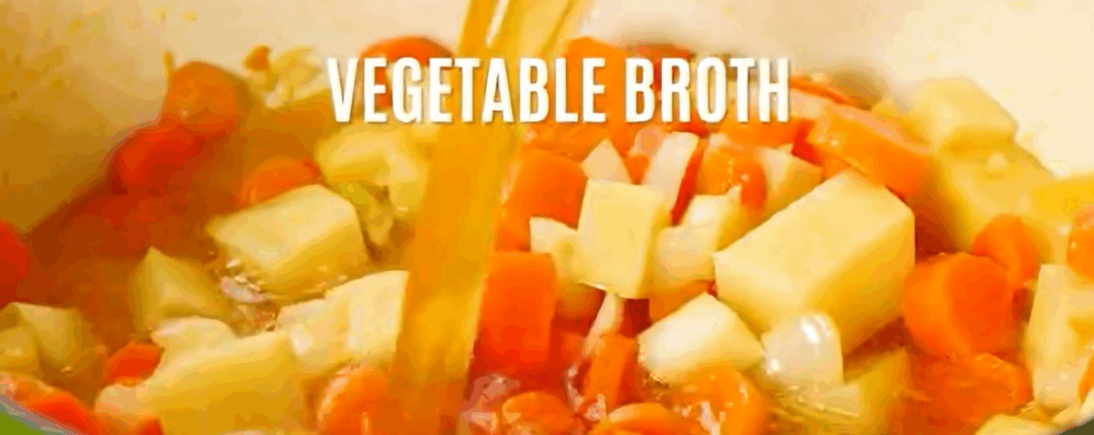 Adding broth to the vegetables in the pot. 