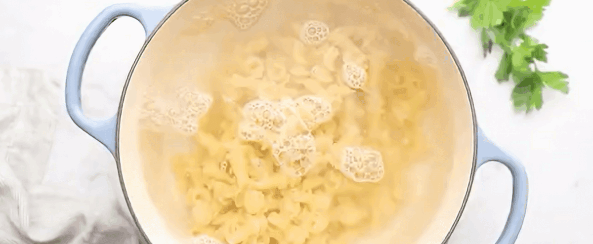 Boiling pasta in a pot with blue handles. 