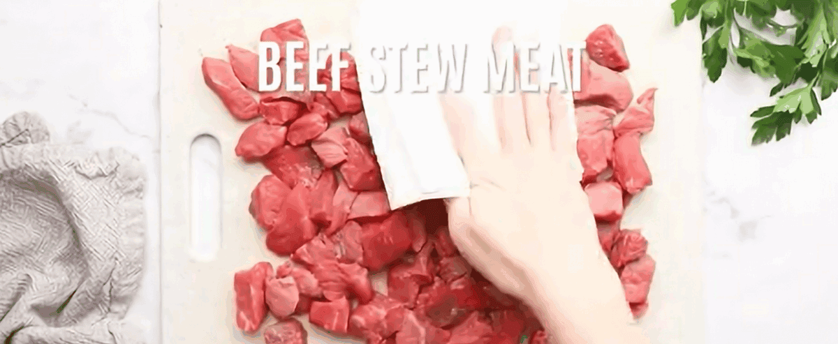Patting beef stew meat with a paper towel.