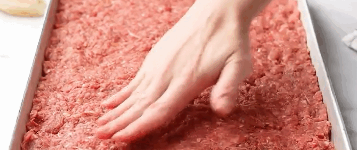 Pressing the beef mixture into the pan.