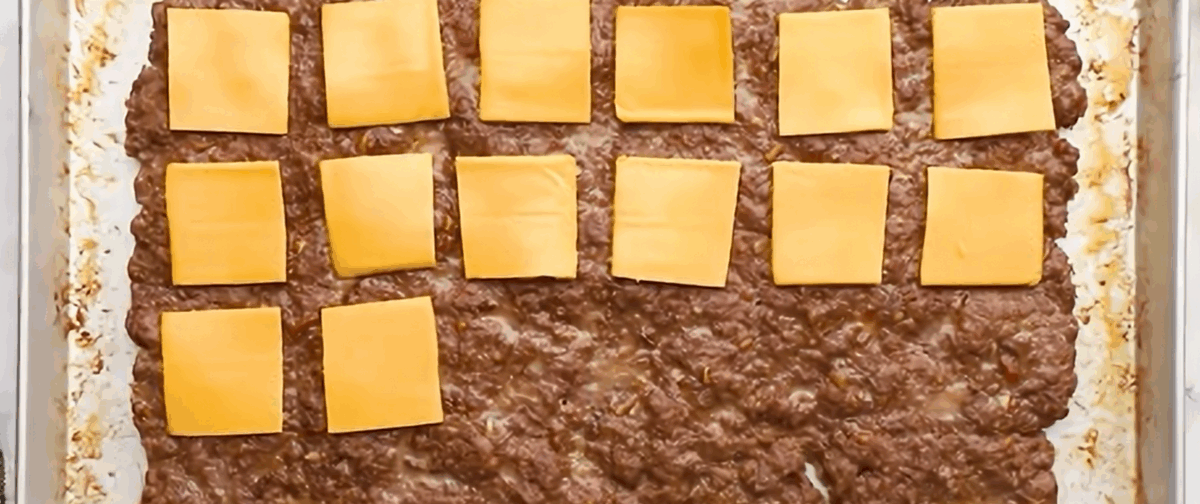 Placing cheese slices onto the cooked meat.