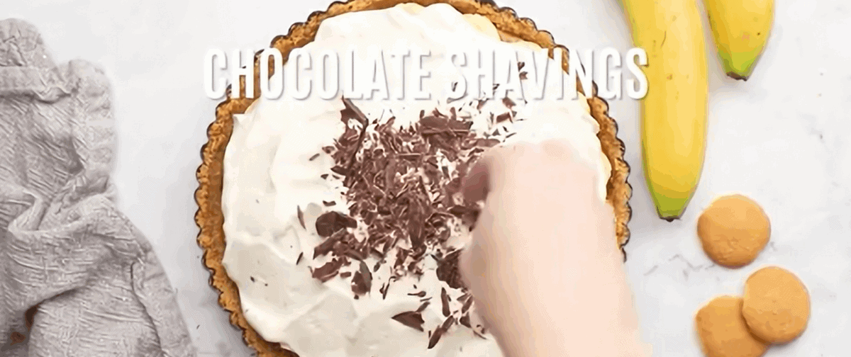 Layering banana slices, whipped cream and chocolate shavings over the dulce de leche. 