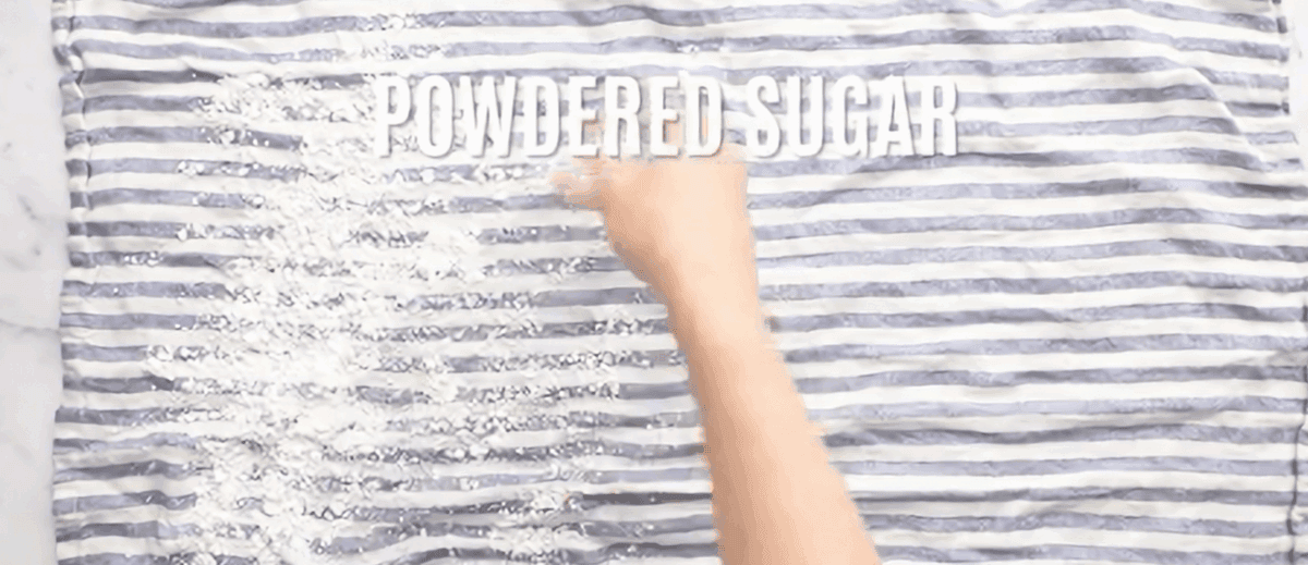 Sprinkling powdered sugar onto a dish towel. 