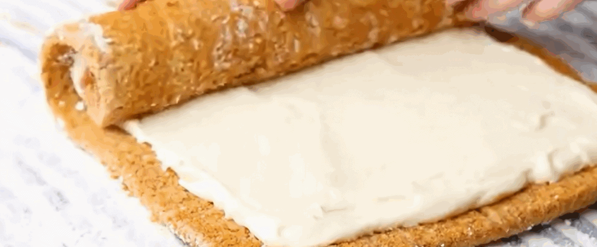 Rolling the cream cheese covered cake back up. 