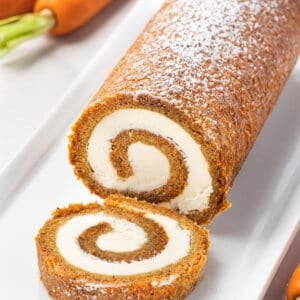 A carrot cake roll with one piece sliced