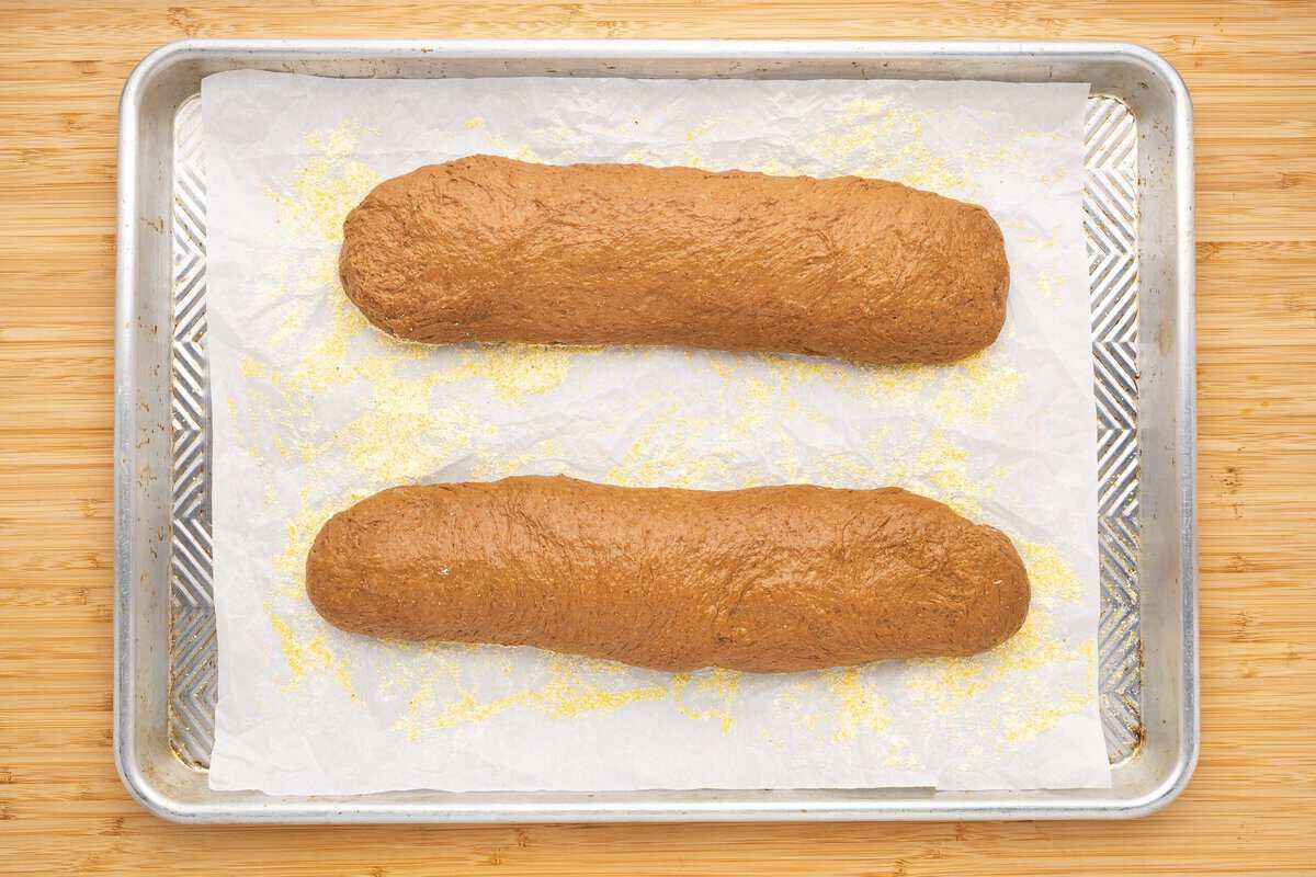 Two logs of dough on a cornmeal covered baking sheet.