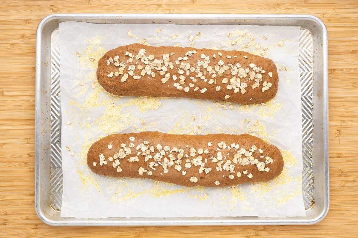 Two loaves on a baking sheet topped with oats.