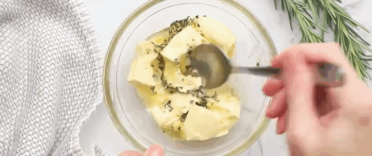 Combining butter, honey and rosemary in a glass bowl.