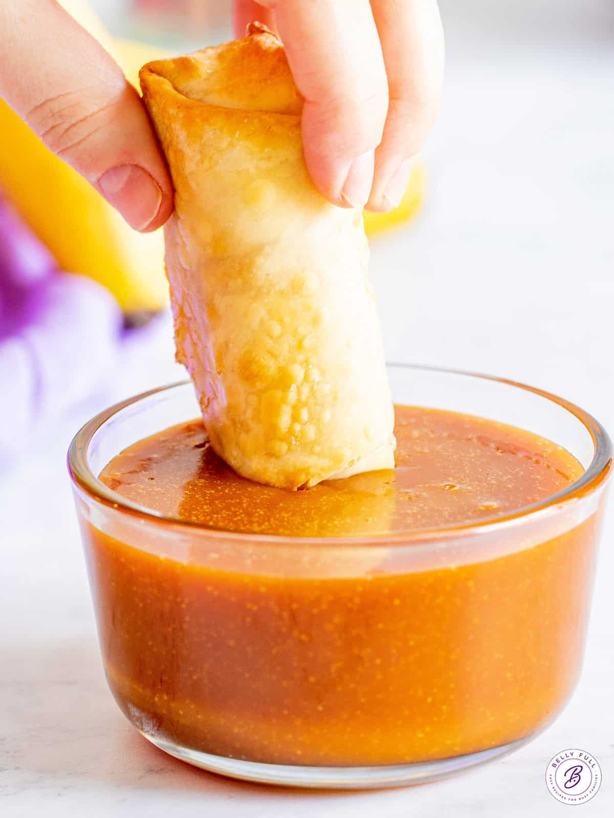 banana lumpia being dunked in caramel sauce