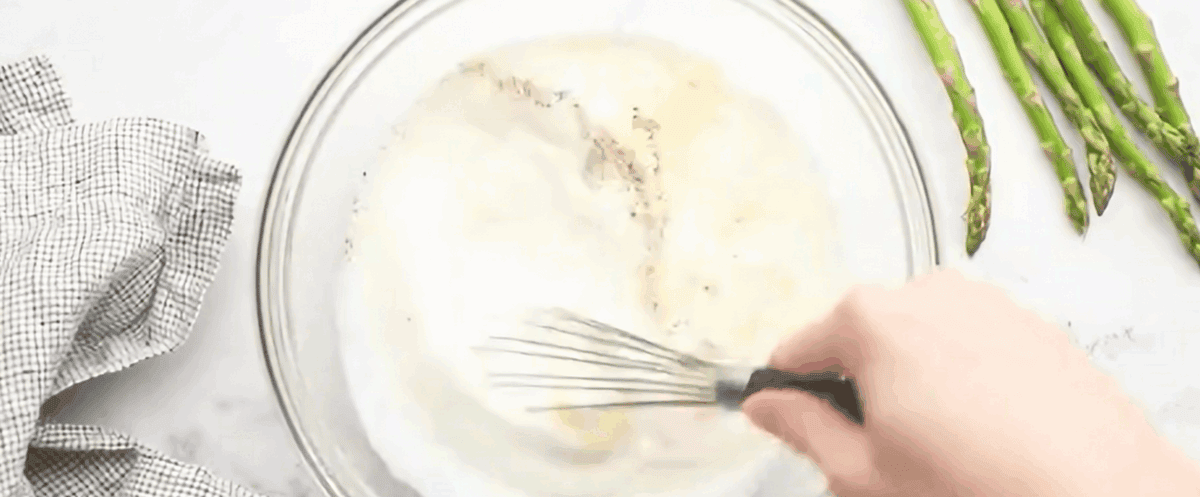 Whisking the egg mixture in a glass bowl.