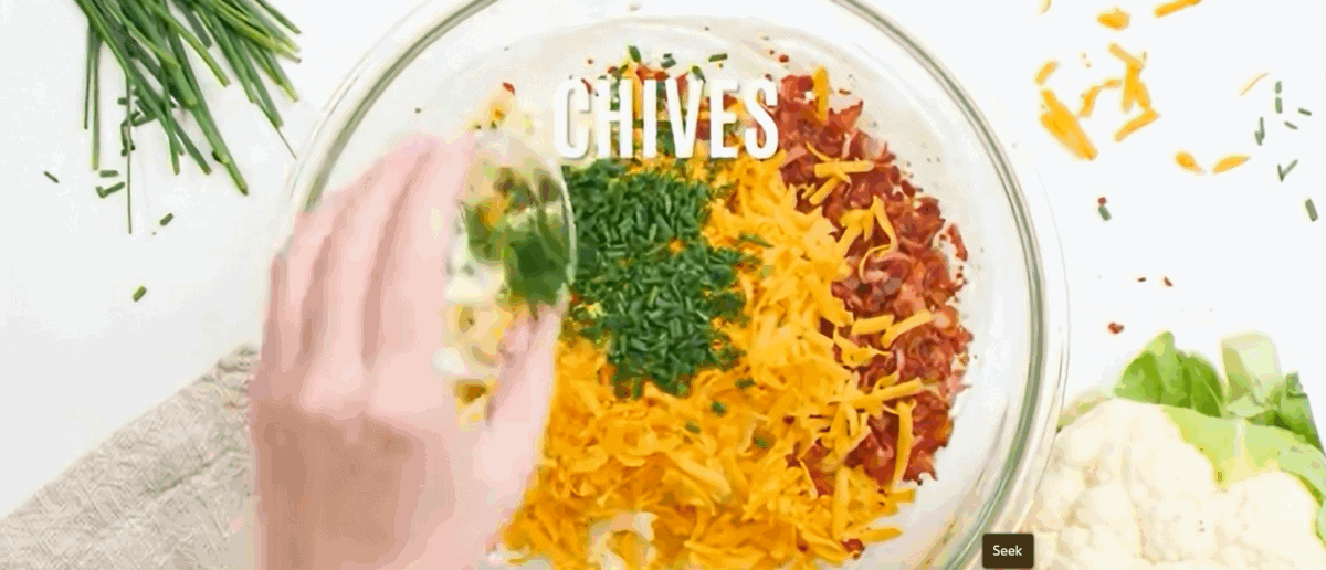 Combining all the ingredients for cauliflower salad in a glass bowl.