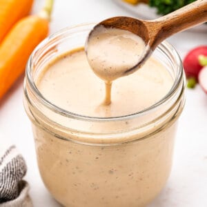 A wooden spoon over a jar of salsa ranch salad dressing