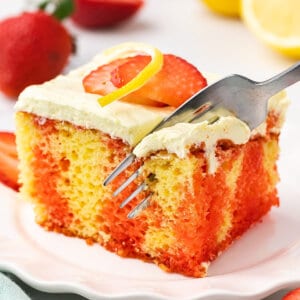 A fork diving into a slice of strawberry lemonade poke cake