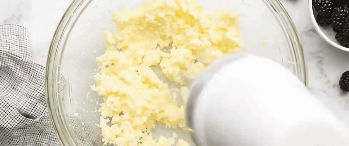 Creaming butter and sugar with an electric hand mixer in a glass bowl.