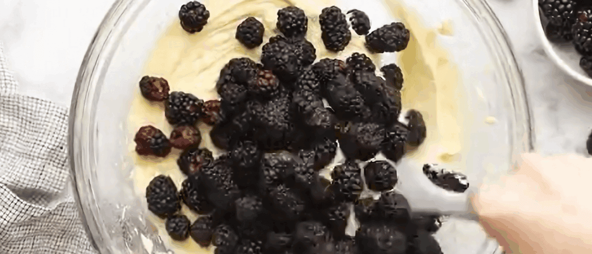 Adding blackberries to the batter.