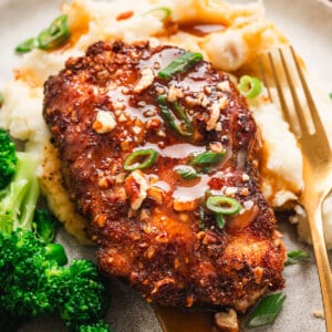 A pecan crusted chicken breast on a plate with potatoes and broccoli