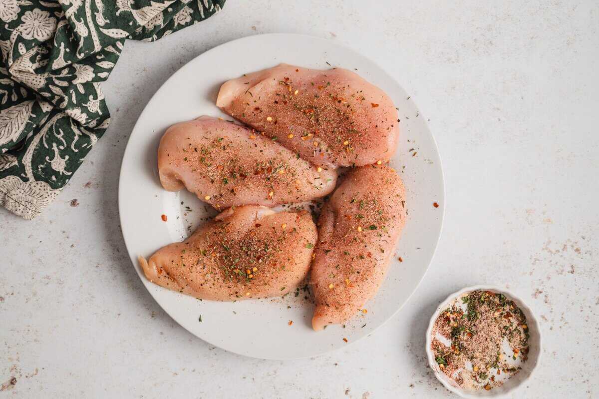 Seasoned chicken breasts on a white plate.