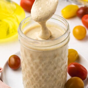 A spoon above a jar of tahini salad dressing