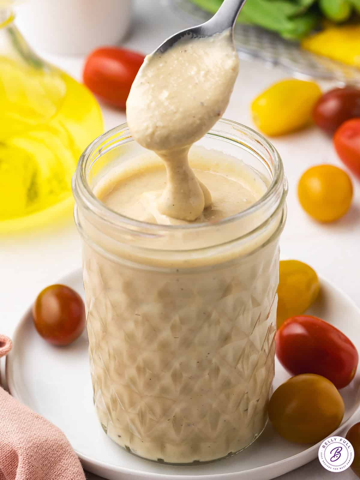 A spoon above a jar of tahini salad dressing