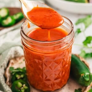 Taking a spoon full of chipotle honey vinaigrette out of a jar.