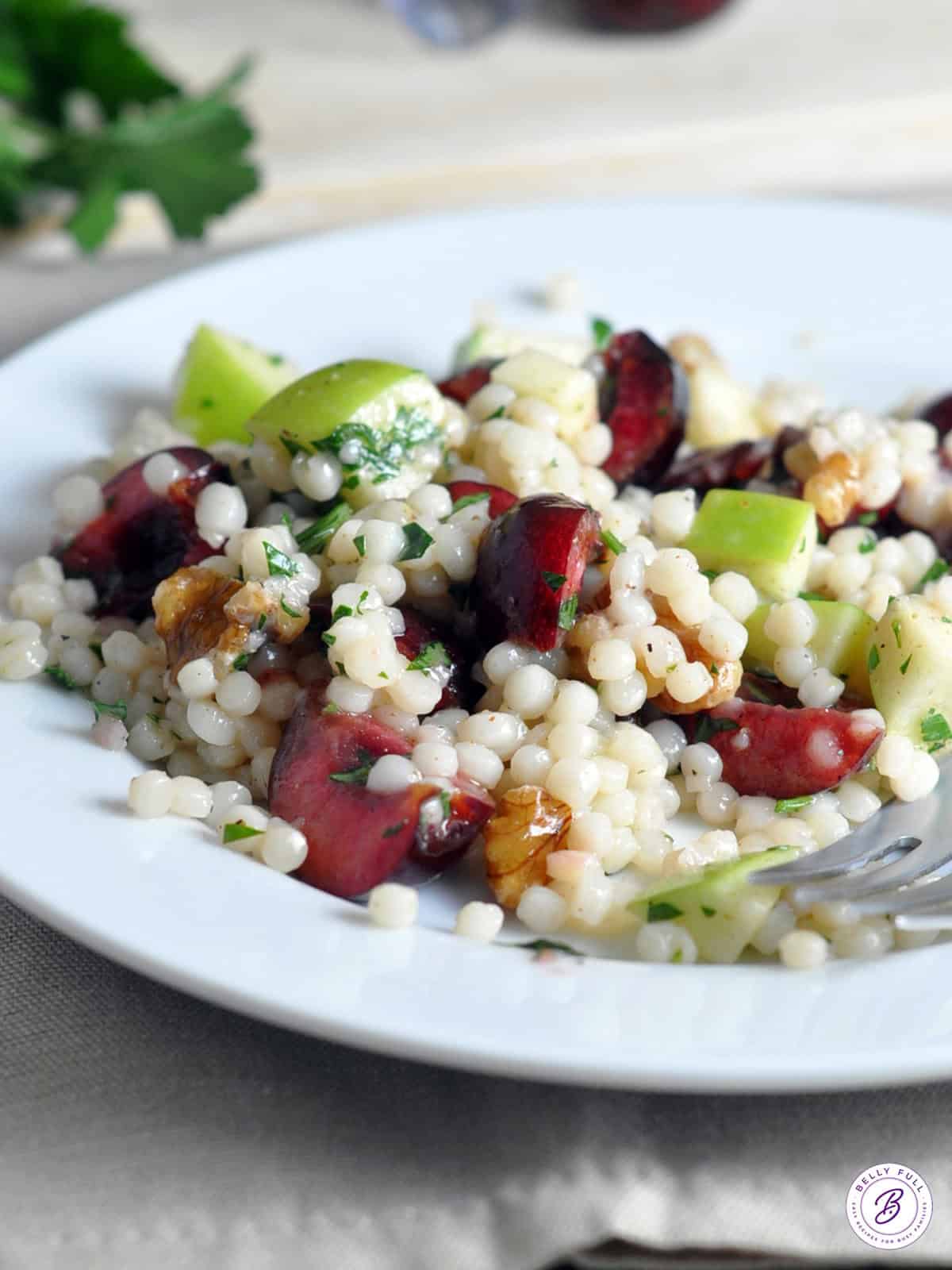 Israeli Couscous with cherries and apples on white plate