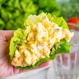 A hand holding pimento cheese egg salad in a lettuce wrap