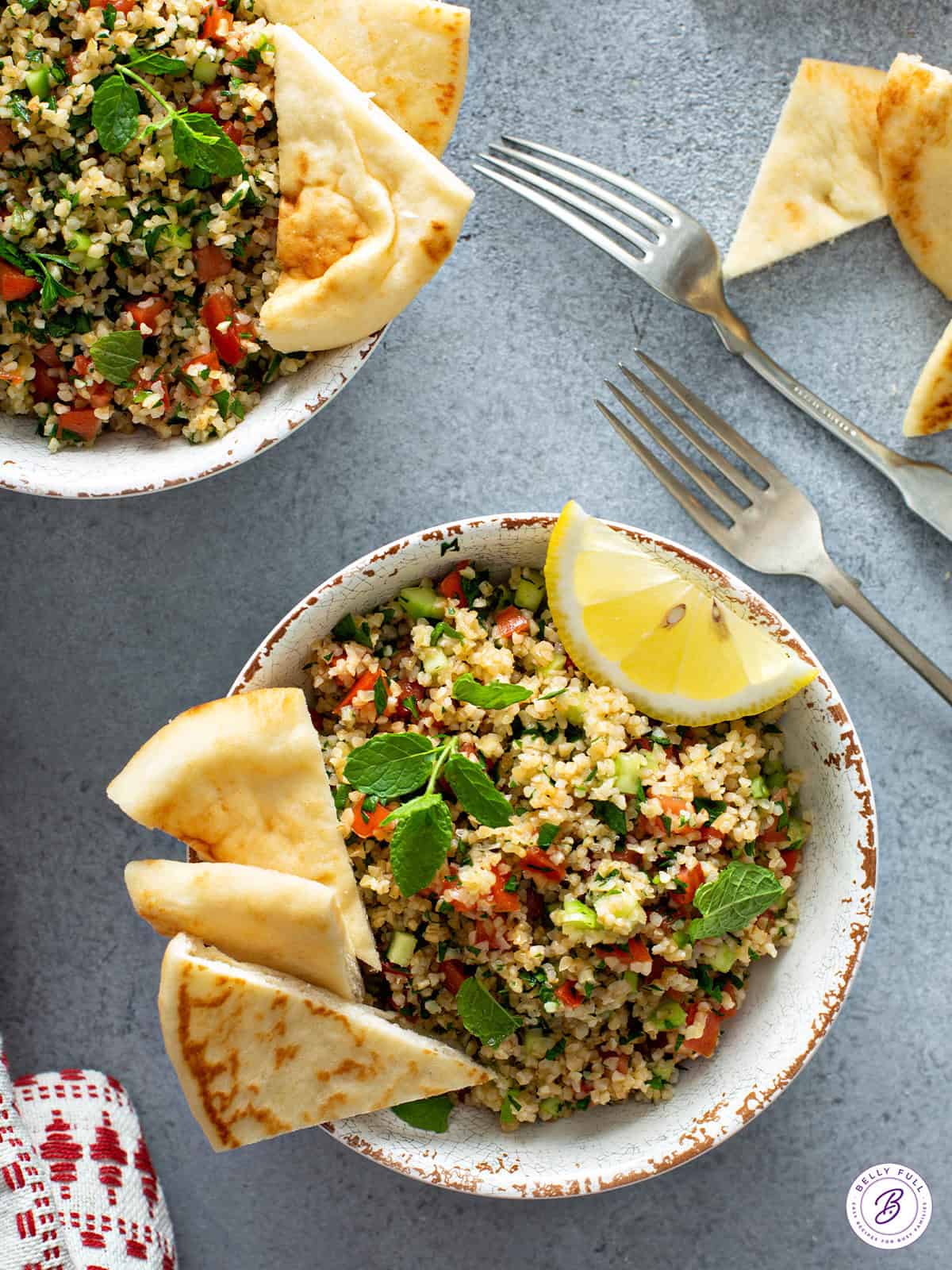 Tabbouleh salad in bowl with lemon wedge and naan