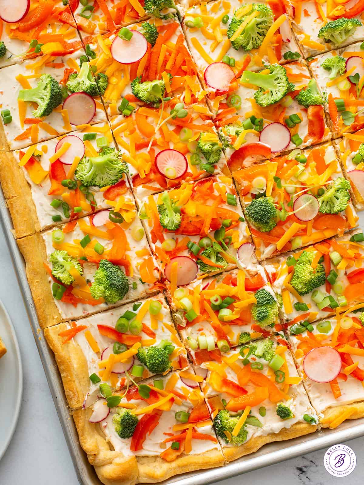 overhead sheet tray of sliced cold veggie pizza