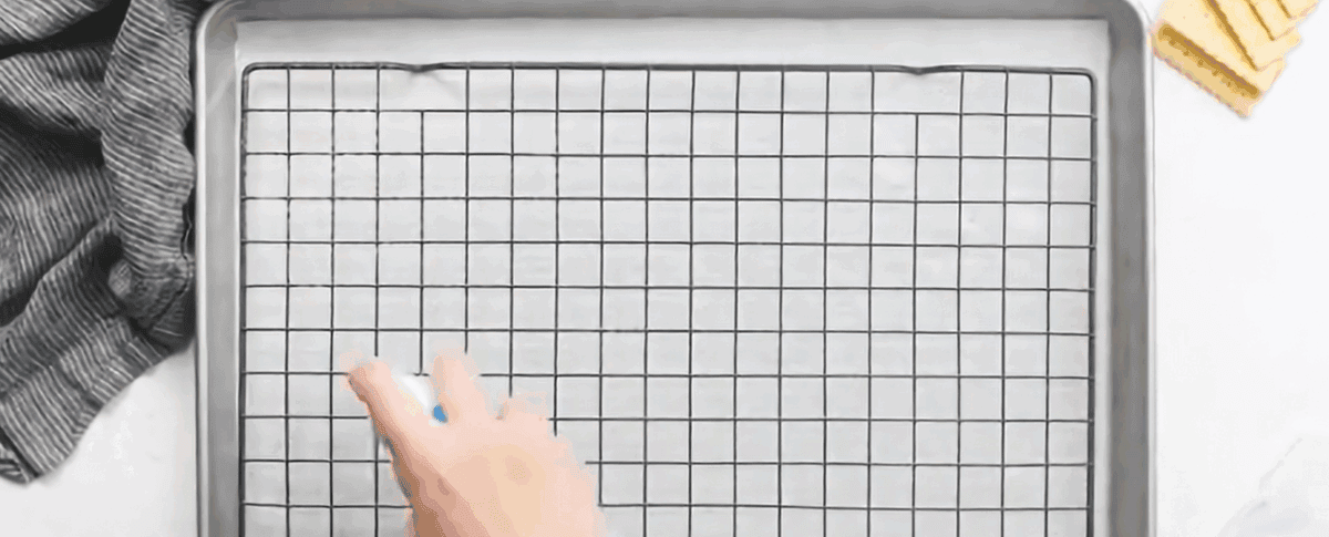 Spraying a wire rack with cooking spray.