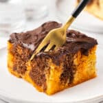 orange and chocolate piece of cake on plate with fork