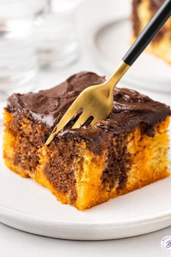 orange and chocolate piece of cake on plate with fork