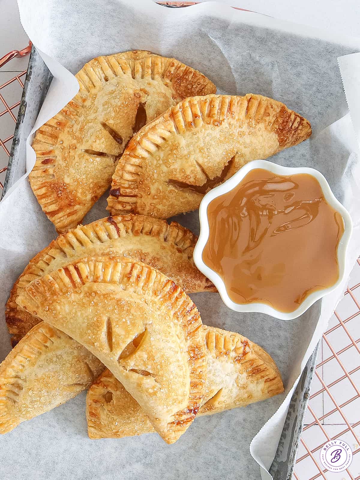 overhead basket of triangle hand pies with bowl of caramel sauce