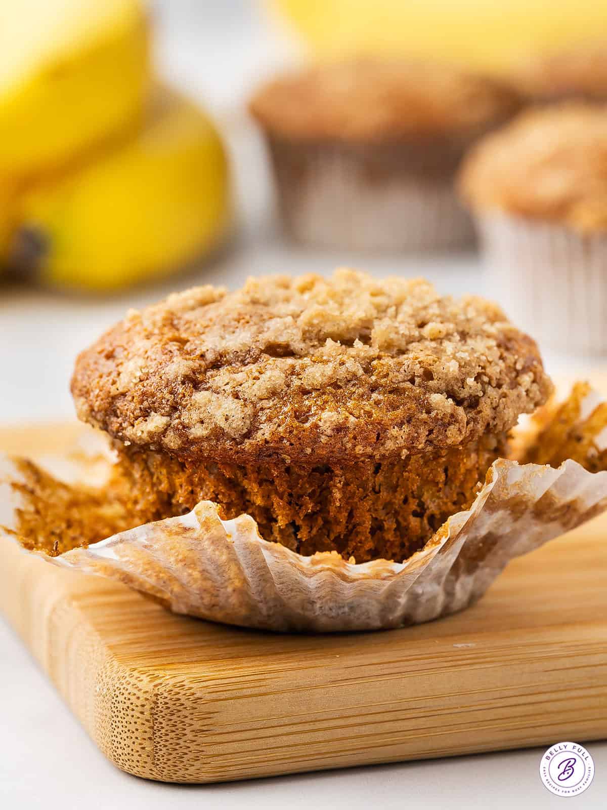 These Banana Crumb Muffins feature an irresistible cinnamon brown sugar topping on an ultra-moist muffin. Quick and easy! A banana crumb muffin with the wrapper pulled down