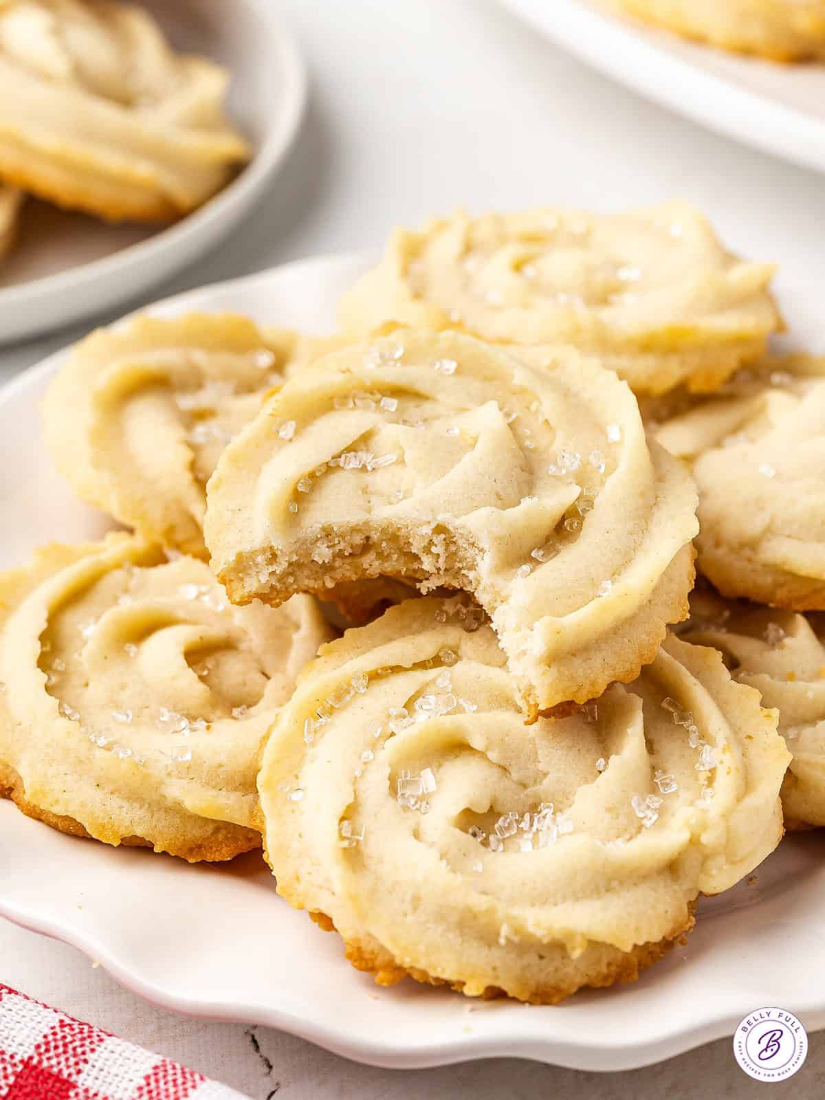 Side view of butter cookies on a plate with one missing a bite.