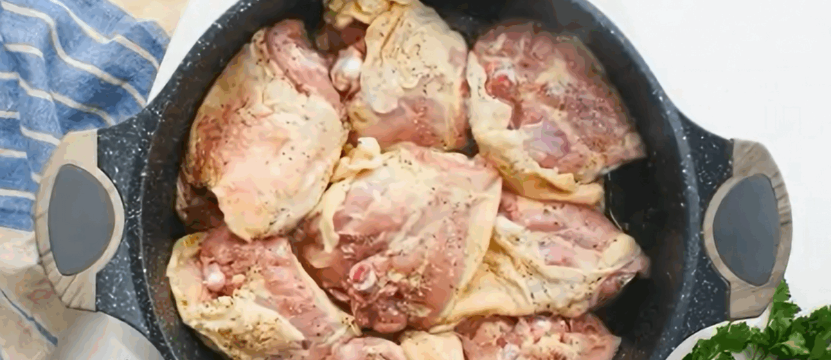 Browning the chicken skin in a black skillet.