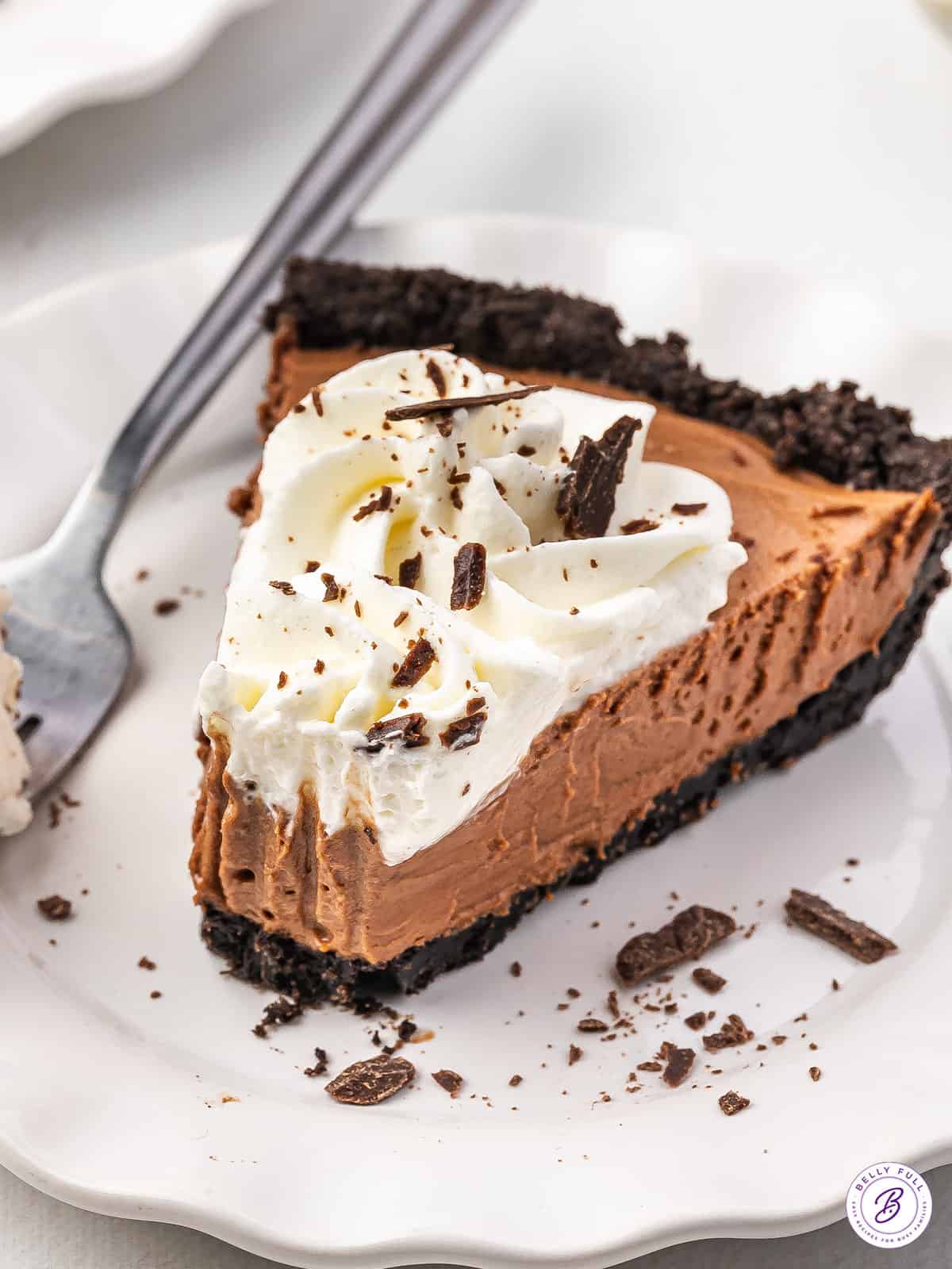 Side view of a slice of french silk pie on a plate with a forkful taken.