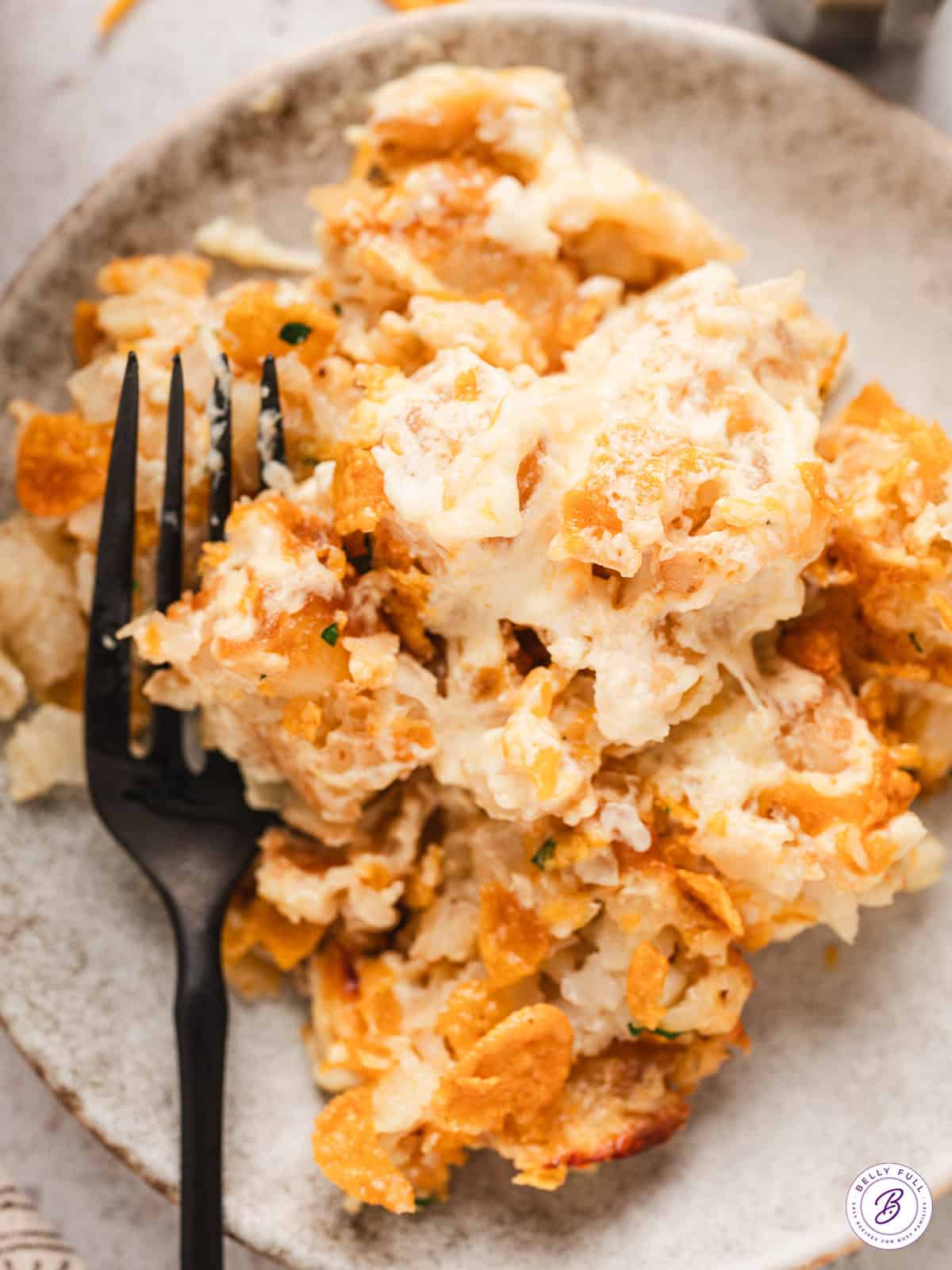 serving on cheesy party potatoes on plate with fork