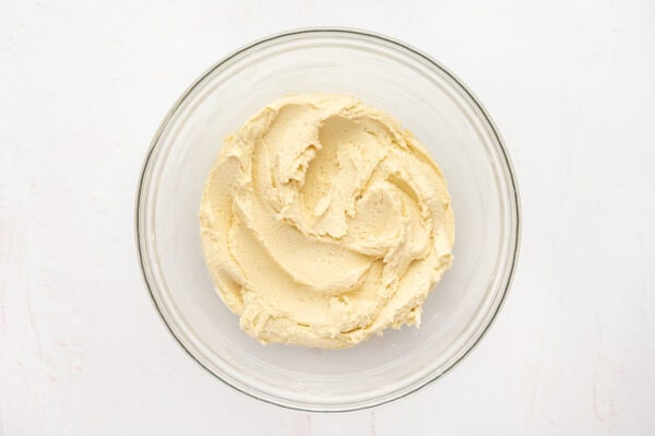 Butter cookie dough with flour added in a glass mixing bowl.