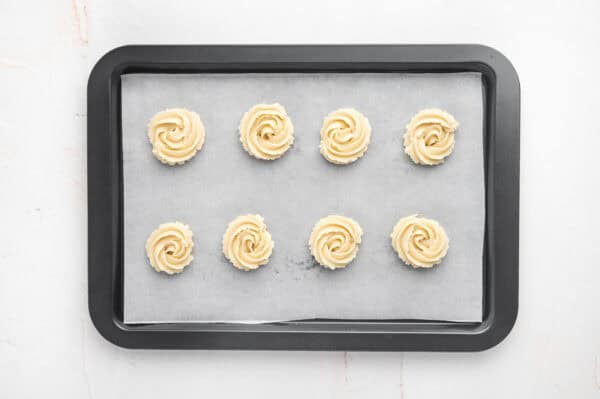 Swirls of butter cookie dough on a parchment lined baking sheet.