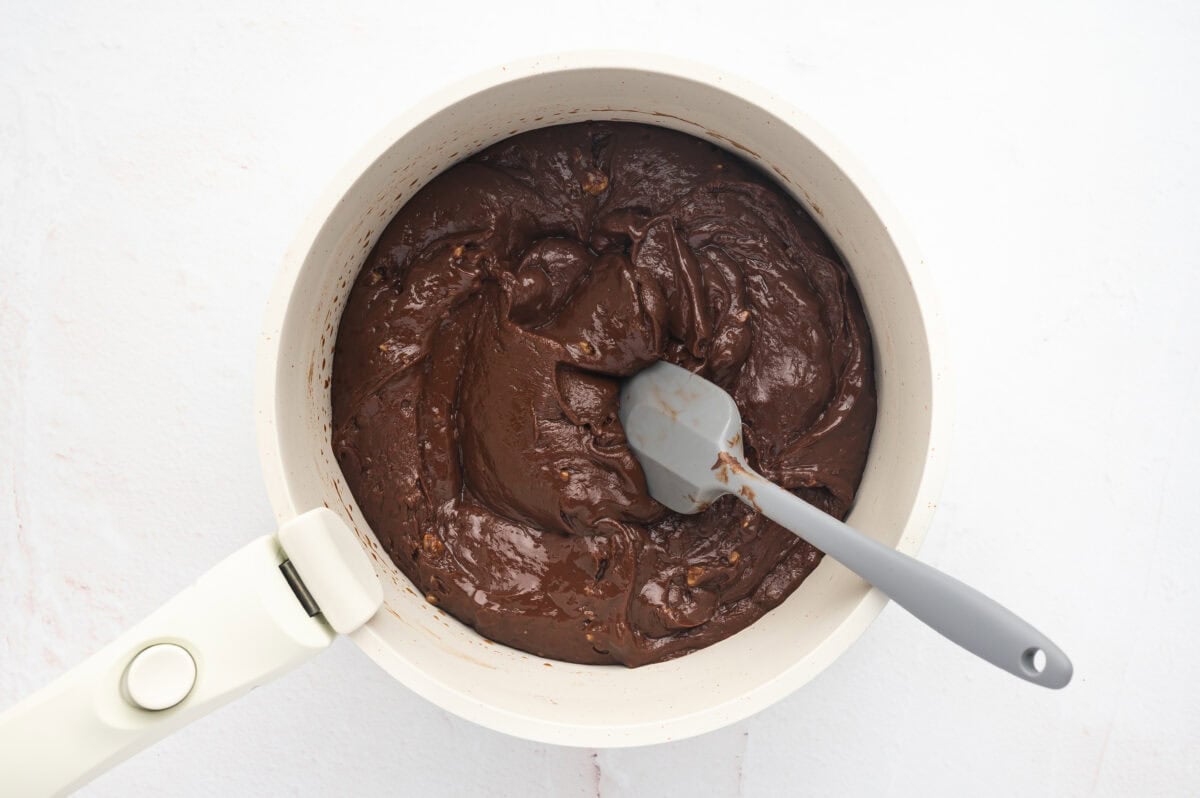 Fudge base mixture in a saucepan with a spatula.